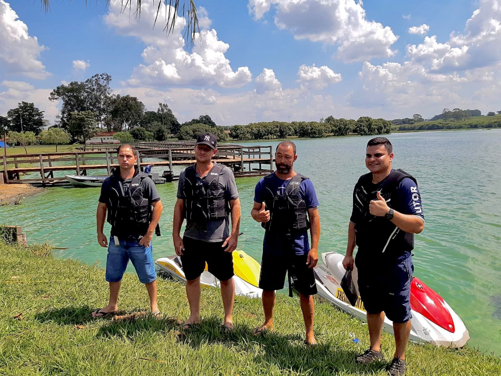 Alunos com coletes ao lado das motos aquáticas, com o píer ao fundo