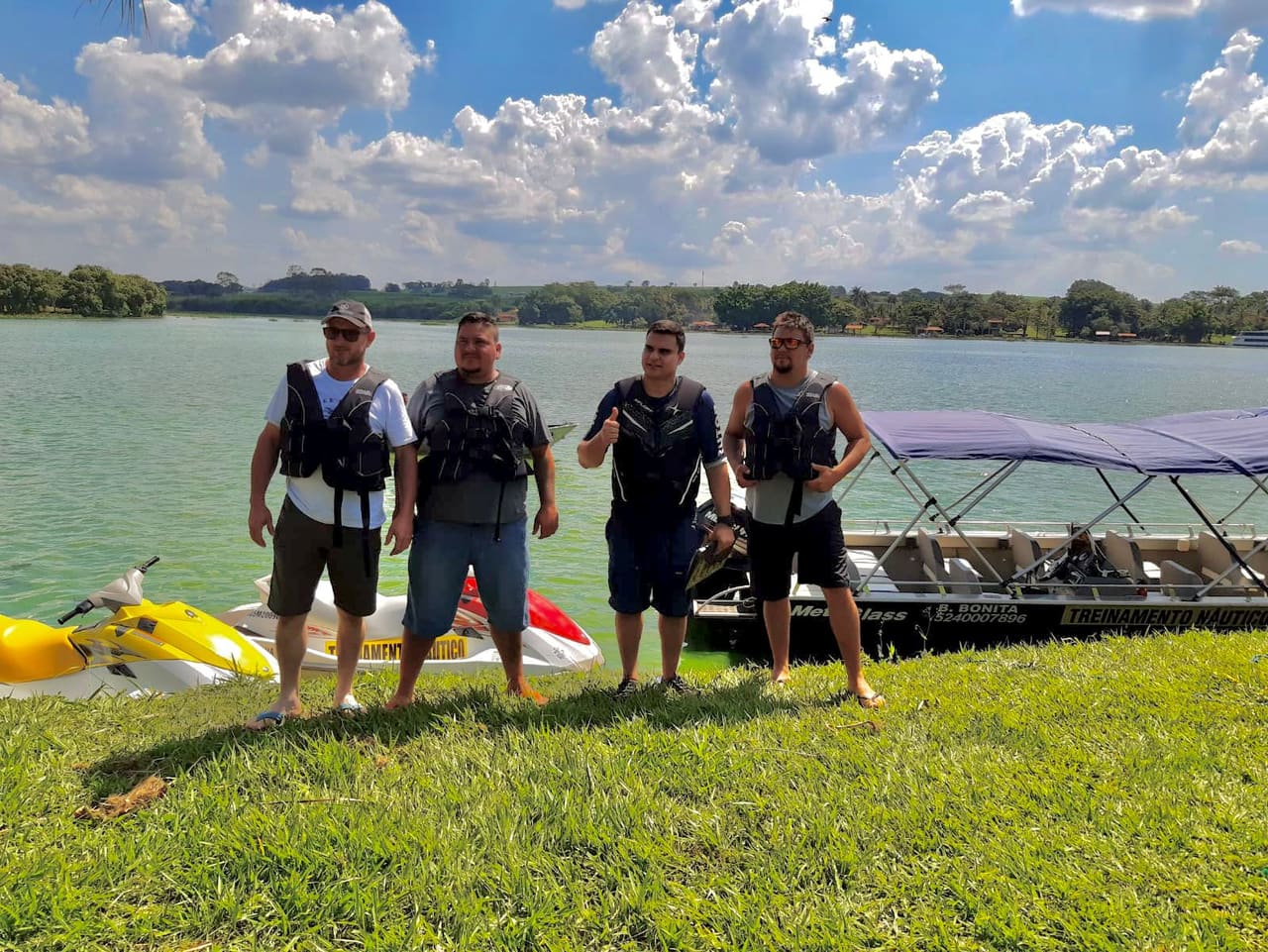Alunos com coletes ao lado das motos aquáticas e da lancha